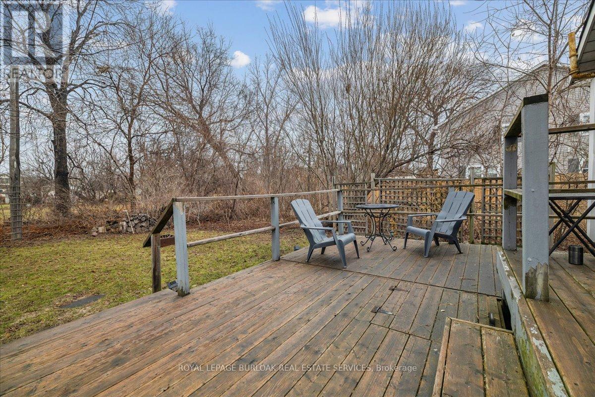 A wooden deck with chairs and a table is surrounded by trees.