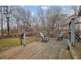 A wooden deck with chairs and a table is surrounded by trees.