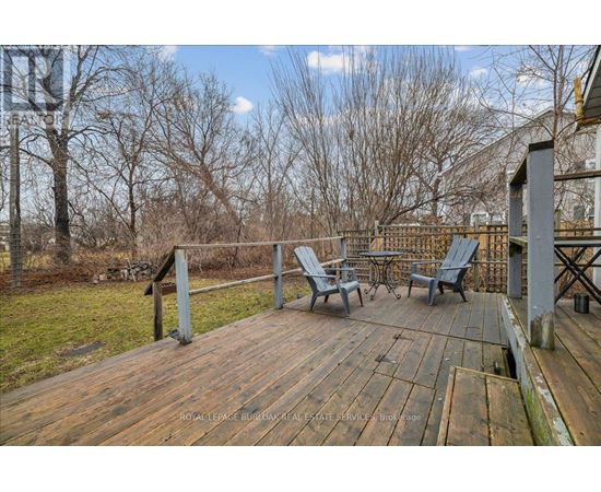 A wooden deck with chairs and a table is surrounded by trees.