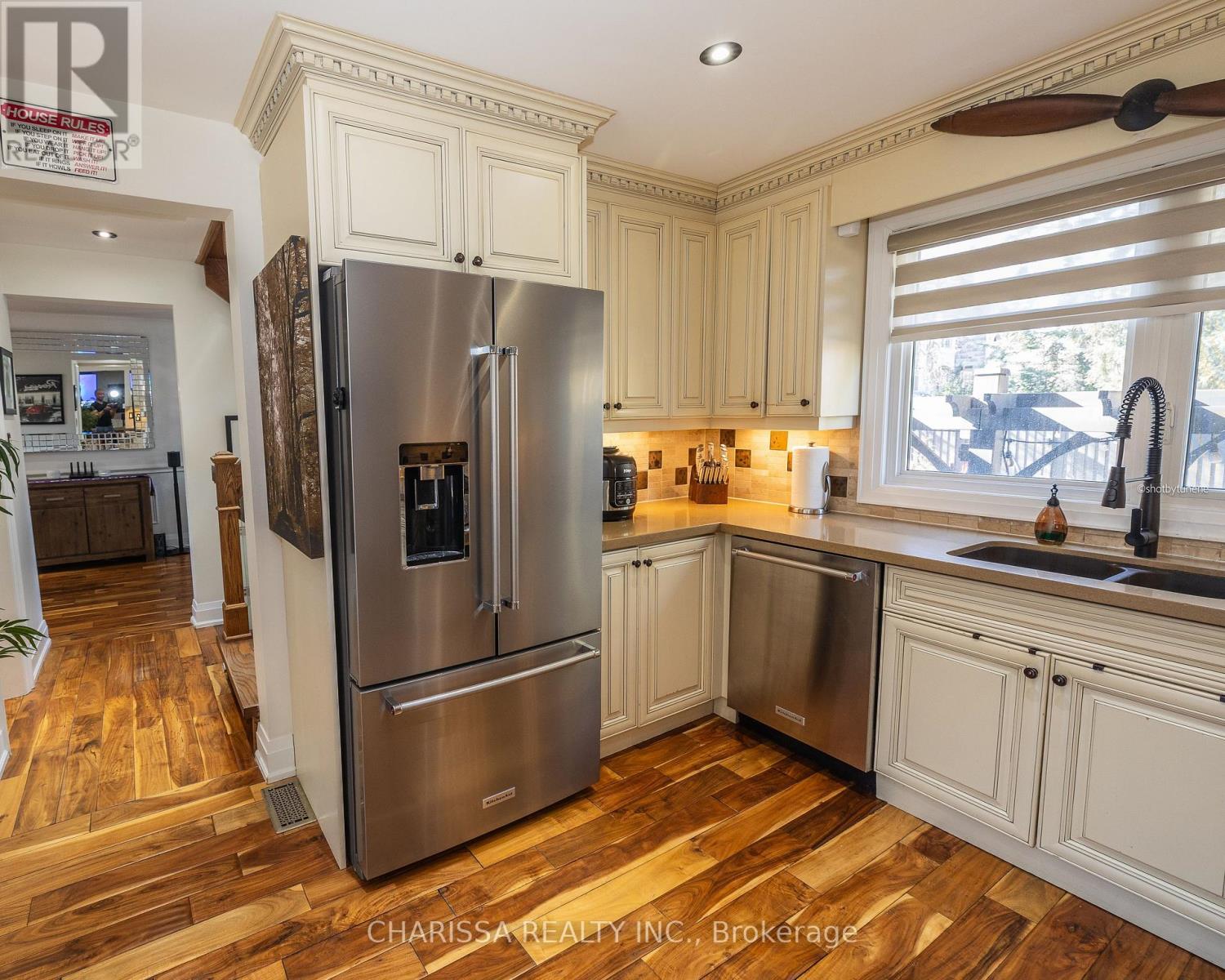 A kitchen with a stainless steel refrigerator and wooden floors.
