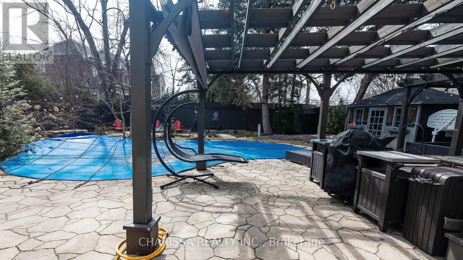 A pool with a blue cover and a pool noodle on the ground.