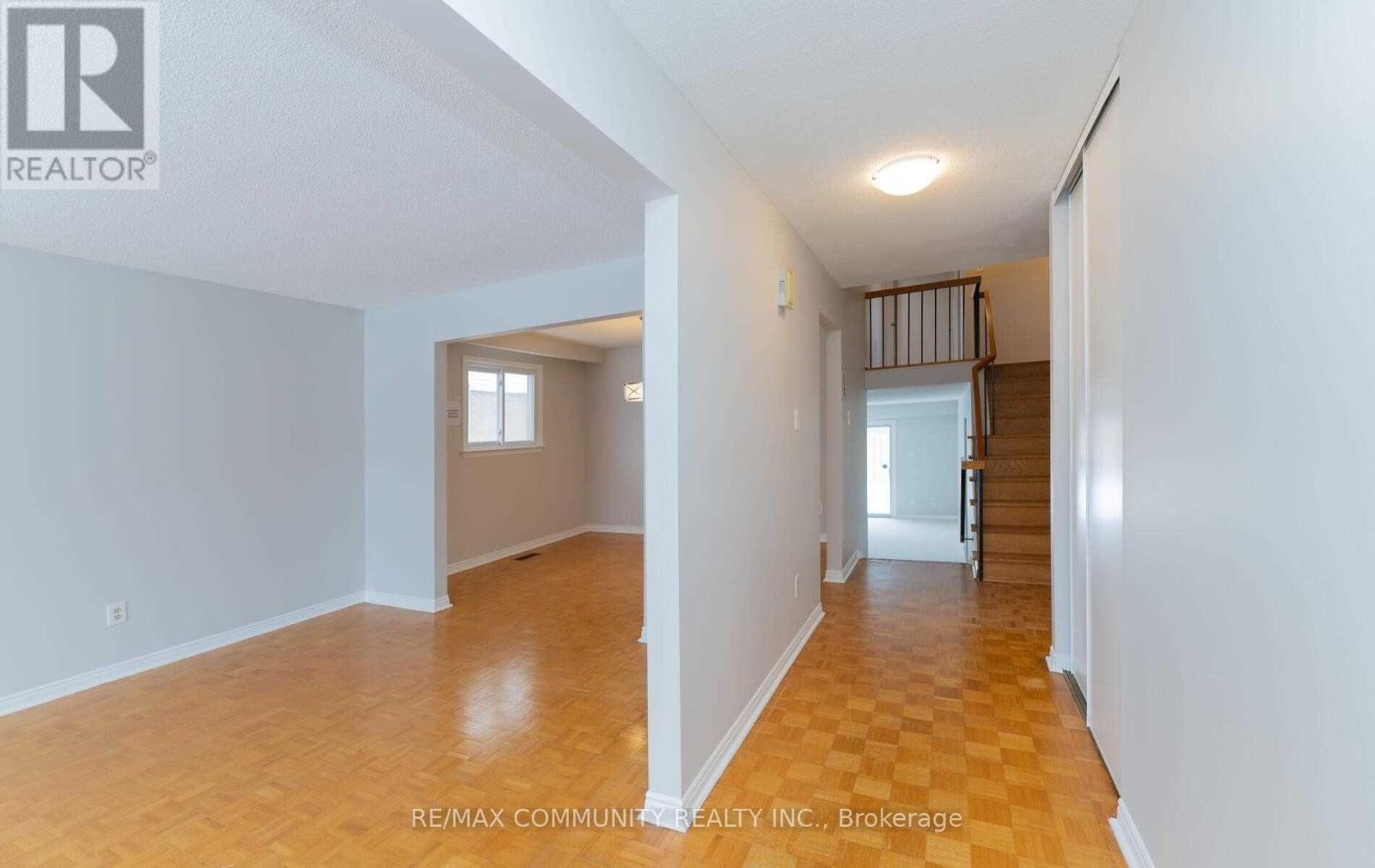A spacious room with wooden floors and white walls, with a doorway leading to another room.