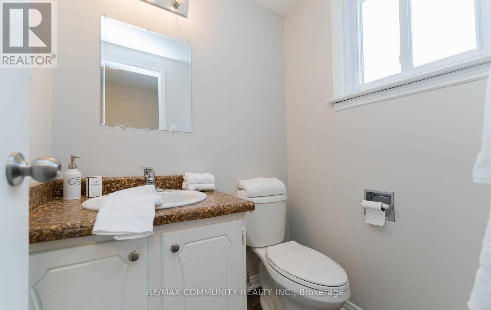 A bathroom with a toilet, sink, and mirror.