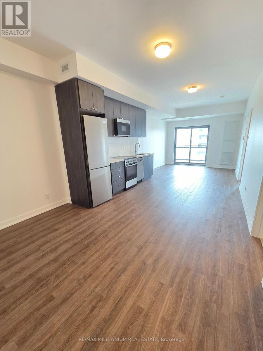 A kitchen with a refrigerator, microwave, and oven.
