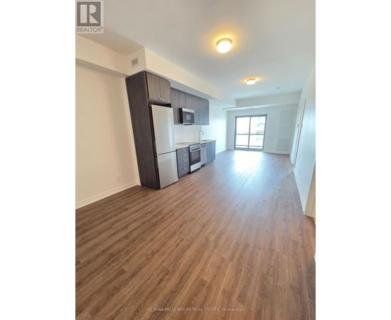A kitchen with a refrigerator, microwave, and oven.