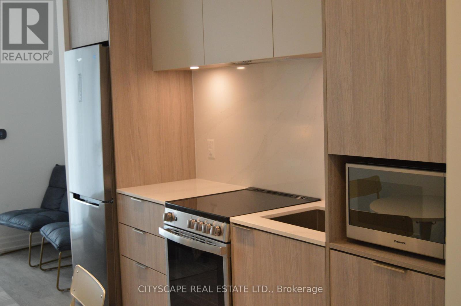 A kitchen with wooden cabinets and a stainless steel refrigerator.