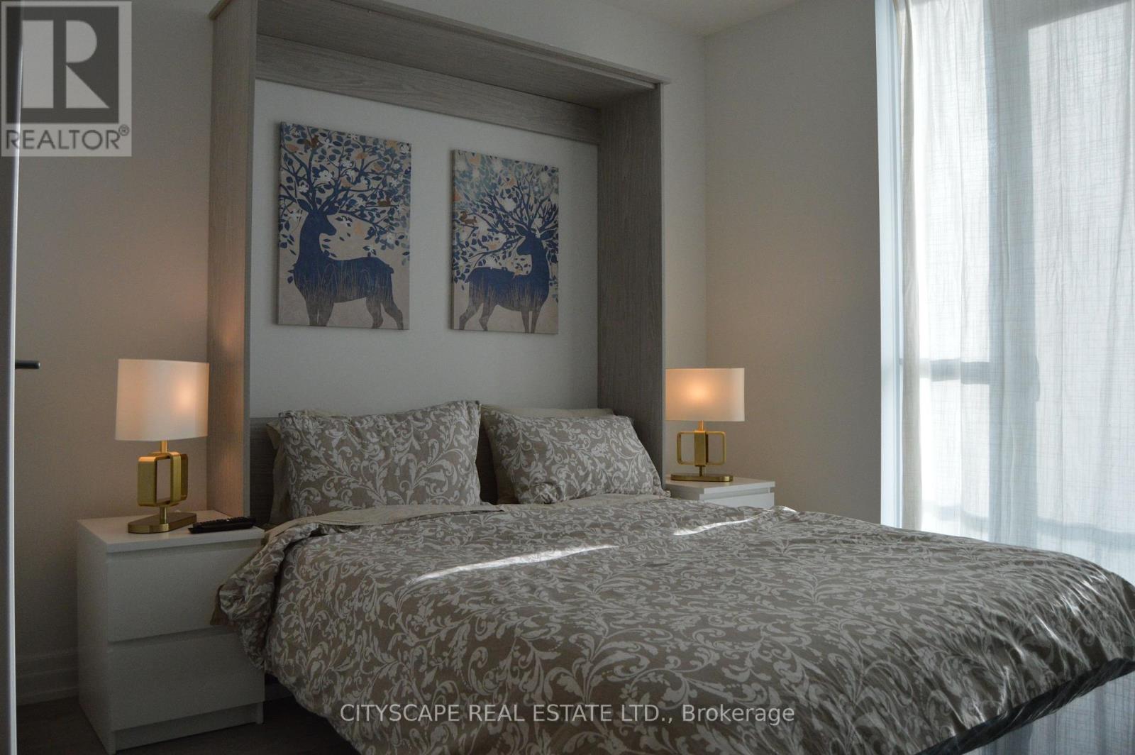 A bedroom with a large bed and two lamps.
