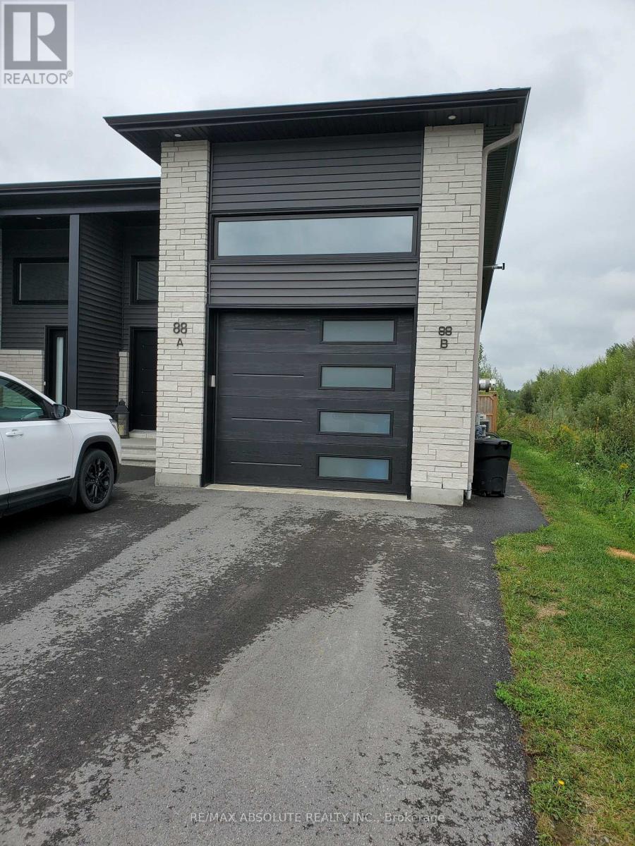 A white car is parked in front of a modern house with a black garage door.