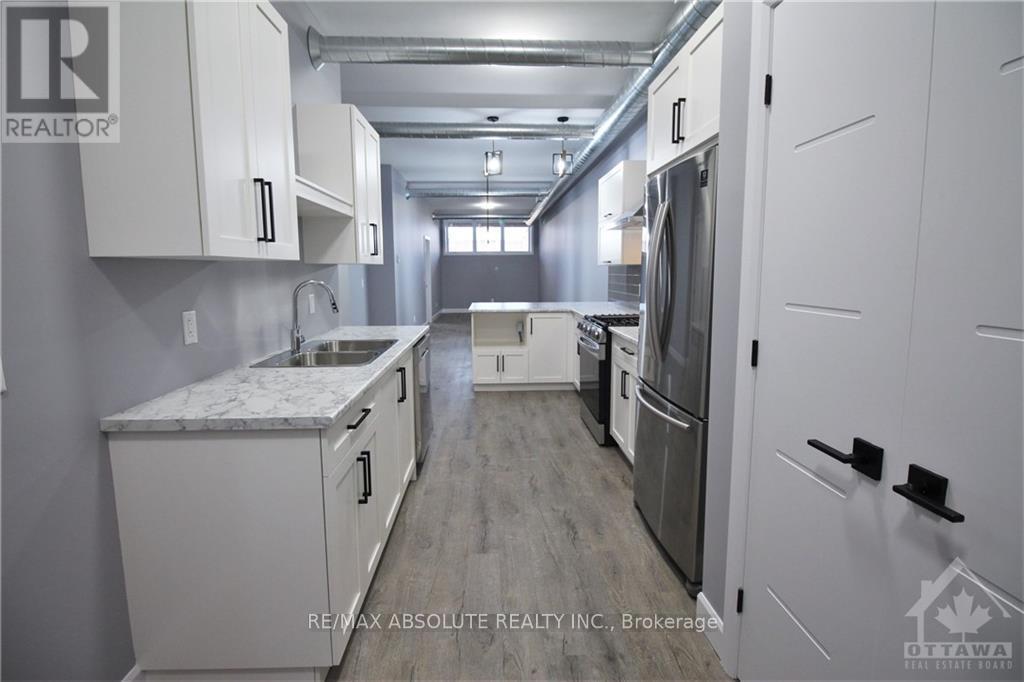 A kitchen with white cabinets and a marble countertop.