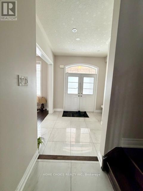 A hallway with a black mat on the floor leading to a door.