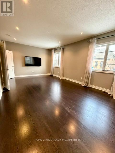 A spacious living room with wood flooring and a flat screen TV mounted on the wall.