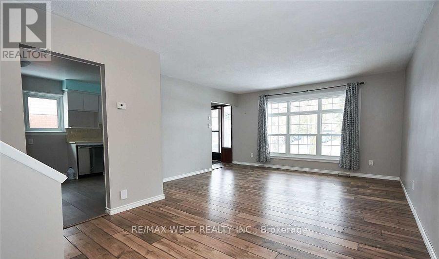 A spacious room with wooden flooring and a large window.