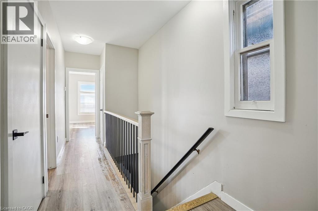 A hallway with a black railing and a window on the wall.