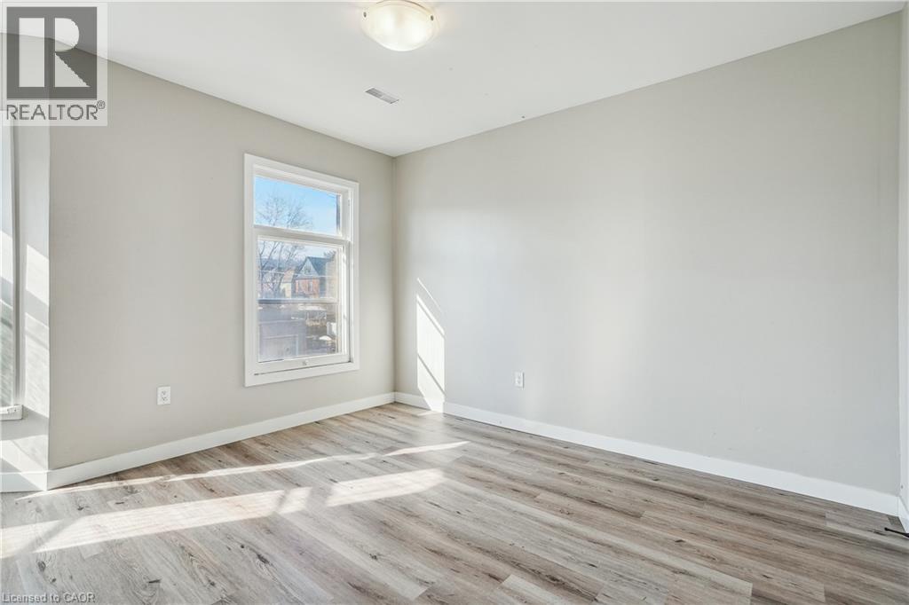 A room with wooden flooring and a window showing a view of a building outside.