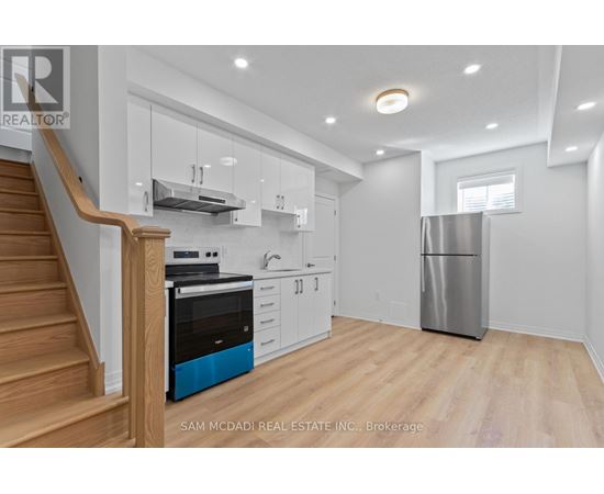 A kitchen with a stainless steel refrigerator and wooden floors.