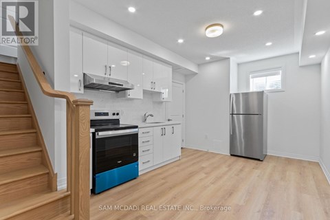 A kitchen with a stainless steel refrigerator and wooden floors.