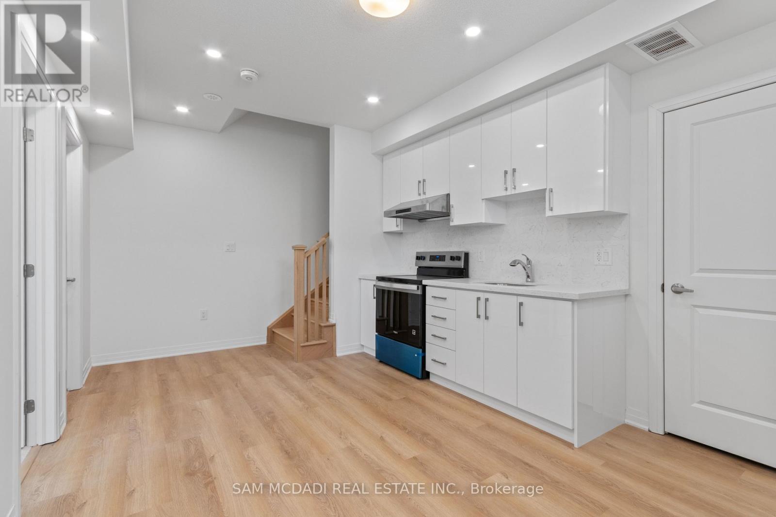 A kitchen with white cabinets and a wooden floor.