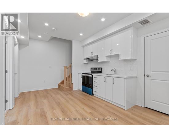 A kitchen with white cabinets and a wooden floor.