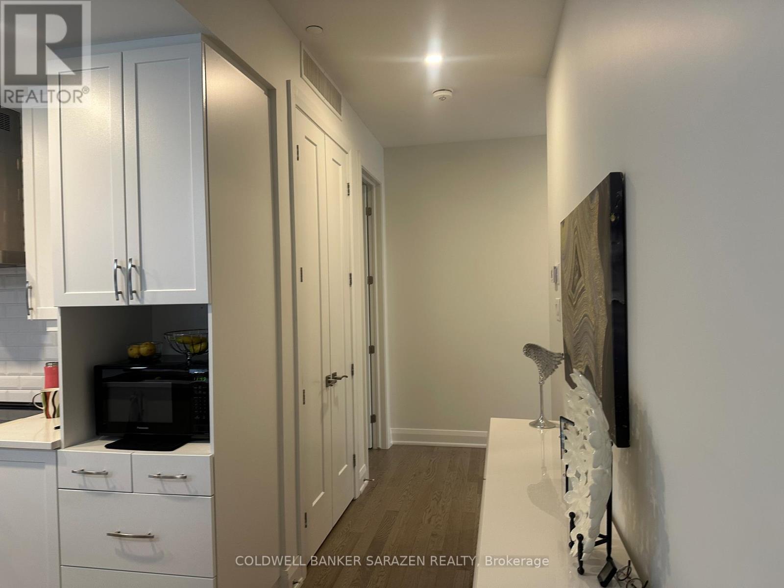 A kitchen with white cabinets and a black microwave.