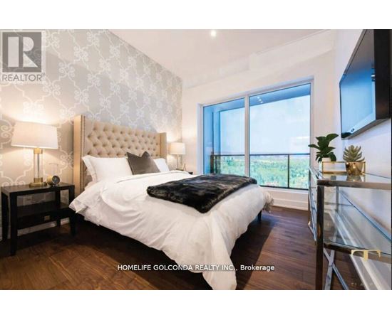 A bedroom with a large bed and a balcony overlooking greenery.