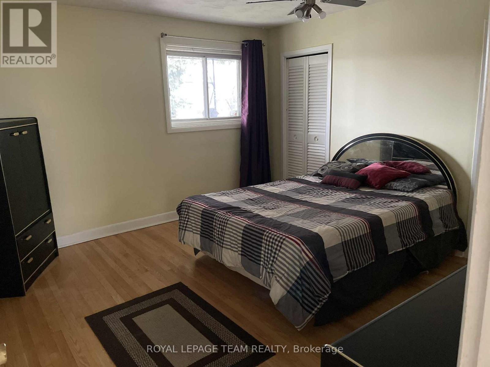 A bedroom with a bed, dresser, and window.