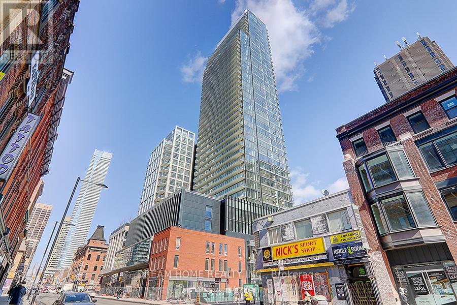 A city street with a tall building in the background and a sign that says "Nick's Sport".