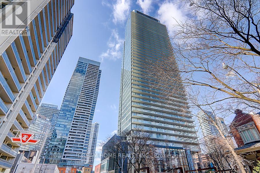 A cityscape with tall buildings and bare trees in the foreground.