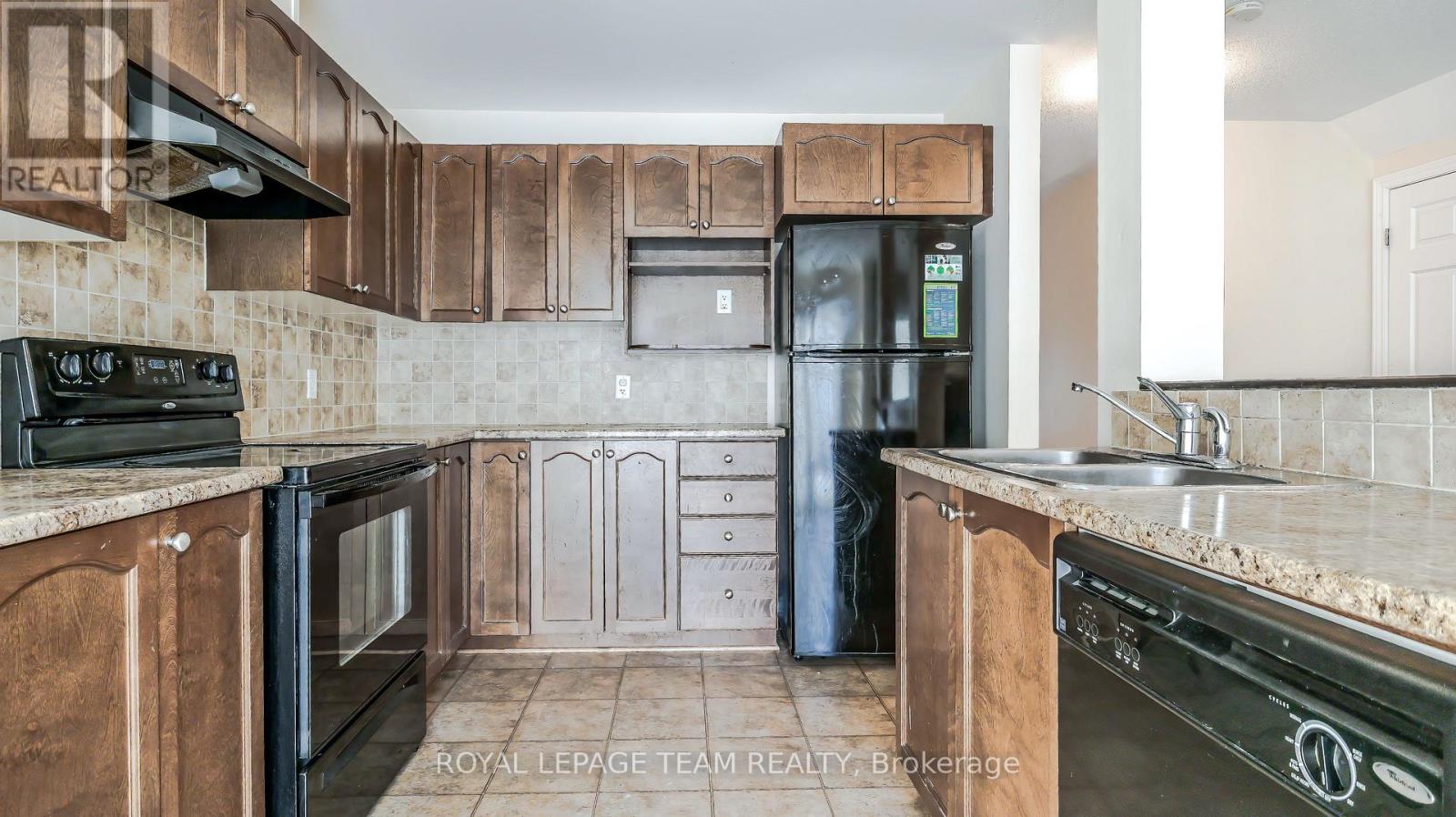 A kitchen with wooden cabinets and a black fridge.