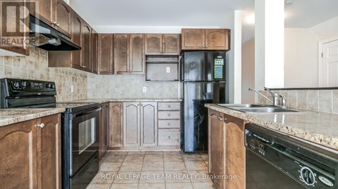 A kitchen with wooden cabinets and a black fridge.