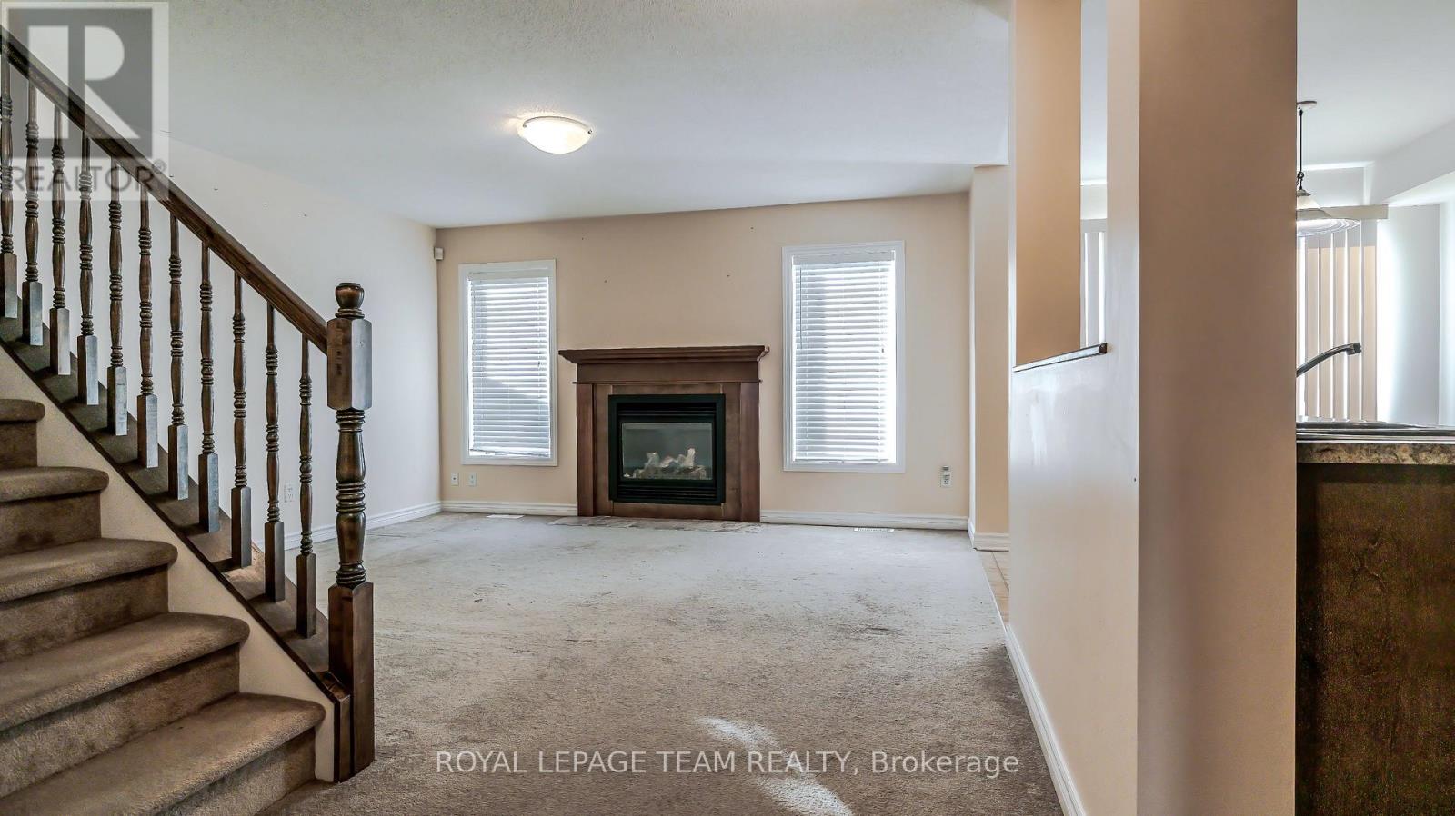 A spacious living room with a staircase leading to the upper floor.