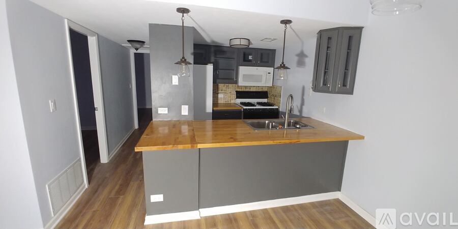 A kitchen with a wooden counter top and grey cabinets.