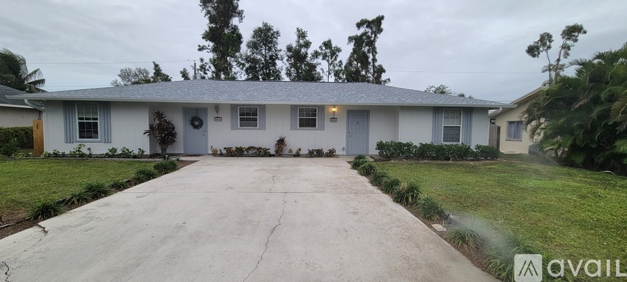 A house with a grey roof and a white wall is available for rent.