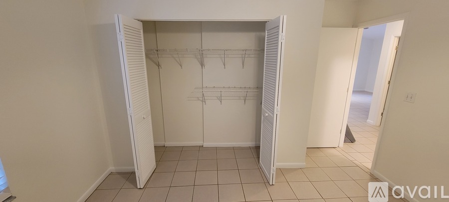 A white closet with clothes hanging on the rack.