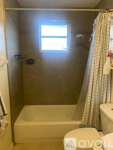 A small bathroom with a white tub and a window.