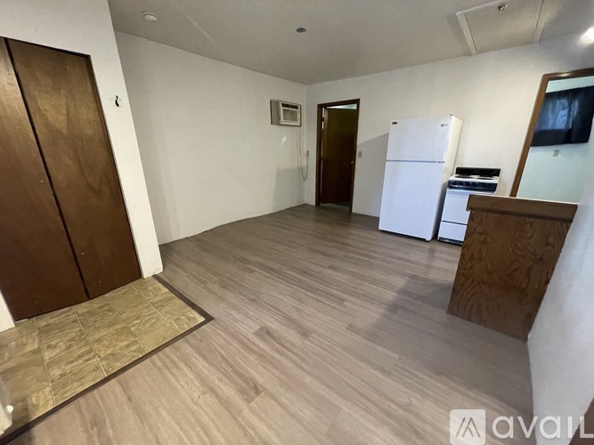 A room with wooden flooring and a white refrigerator.