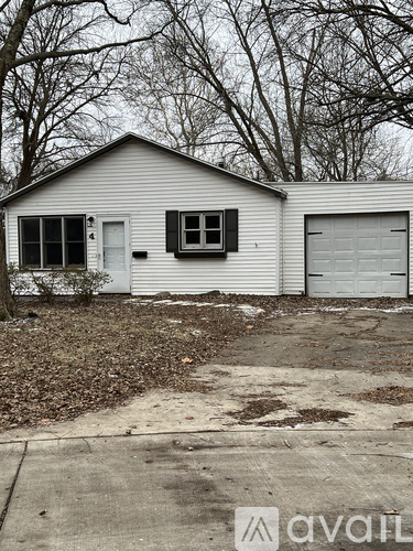 A small white house with a grey roof and a closed white garage door.