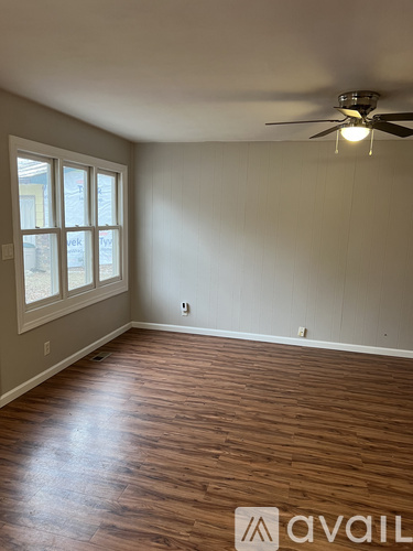 A room with wooden flooring and a ceiling fan.
