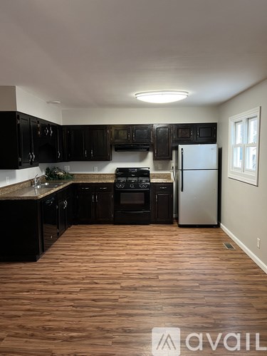 A kitchen with black cabinets and a wooden floor.
