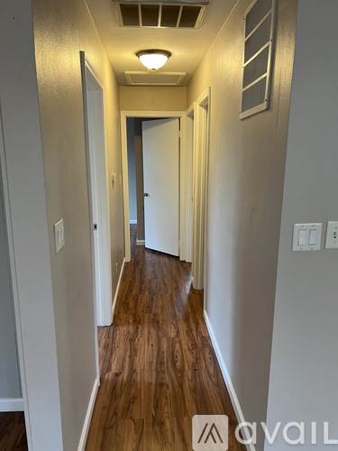 A long hallway with wood floors and white walls.