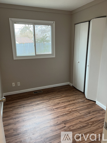 A room with a window and wooden flooring.