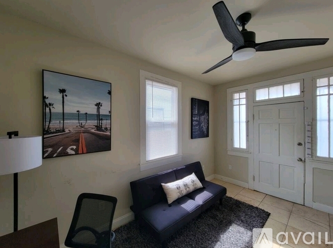 A living room with a black couch and a ceiling fan.