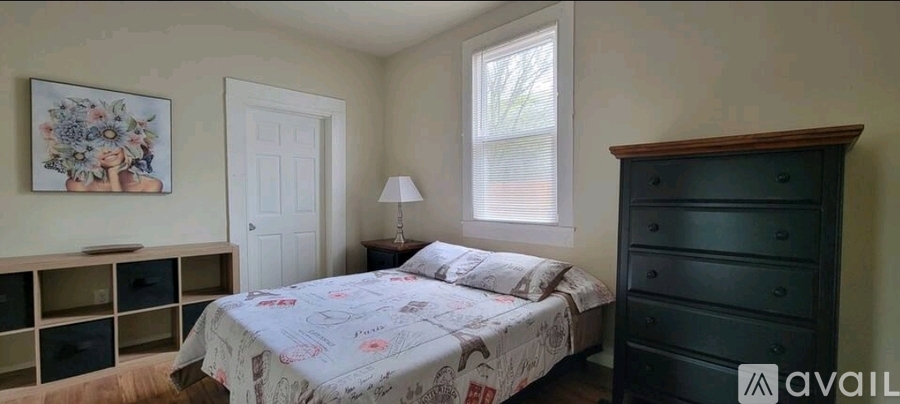 A bedroom with a bed, dresser, and a window.