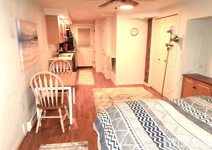 A bedroom with a bed, a chair, and a clock on the wall.
