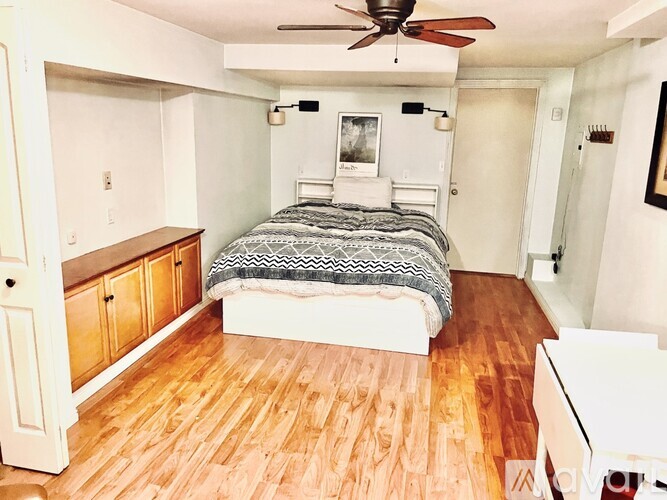 A bedroom with a bed, dresser, and a ceiling fan.