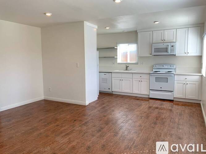 A kitchen with white cabinets and a wooden floor.