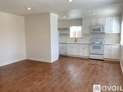 A kitchen with white cabinets and a wooden floor.