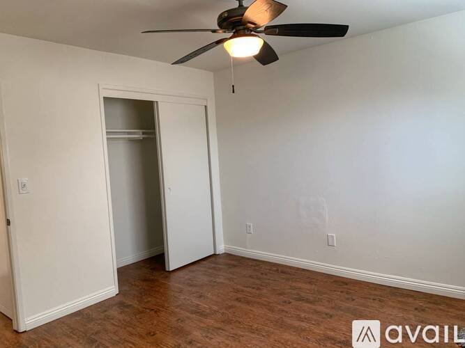 A room with a ceiling fan and a doorway leading to another room.
