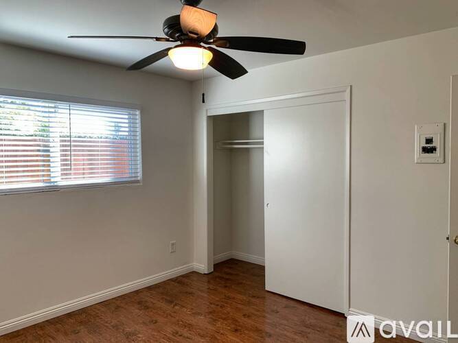 A room with a ceiling fan and a window with blinds.