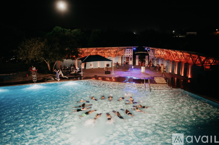 A group of people are swimming in a pool at night.