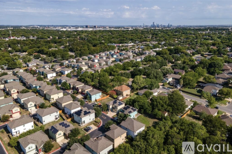 A suburban neighborhood with houses and trees, with a city skyline in the distance.